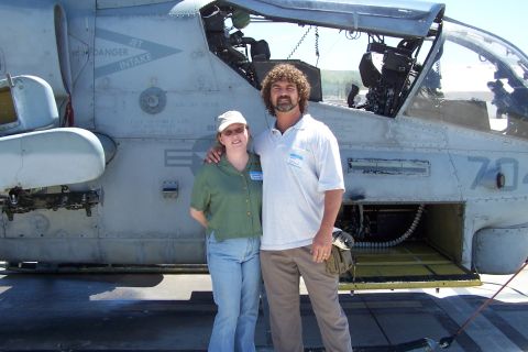 1990 Ford Bronco - Two individuals pose for a photo in front of a military helicopter, which appears to be a Bell AH-1 Cobra.
