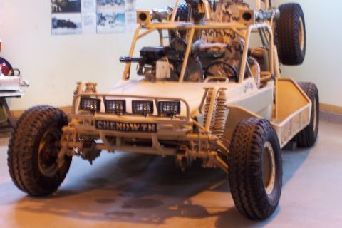 1990 Ford Bronco - A military-style dune buggy with "CHENOWTH" visible on the front bumper is parked indoors.