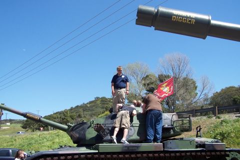 1990 Ford Bronco - A military tank with text on its barrel is viewed outdoors with people interacting with it.