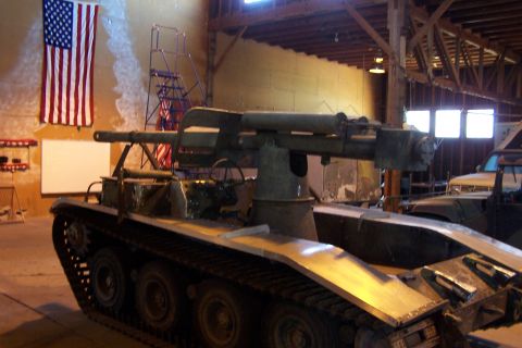 1990 Ford Bronco - Military tank with cannon inside a building, American flag visible on the wall.