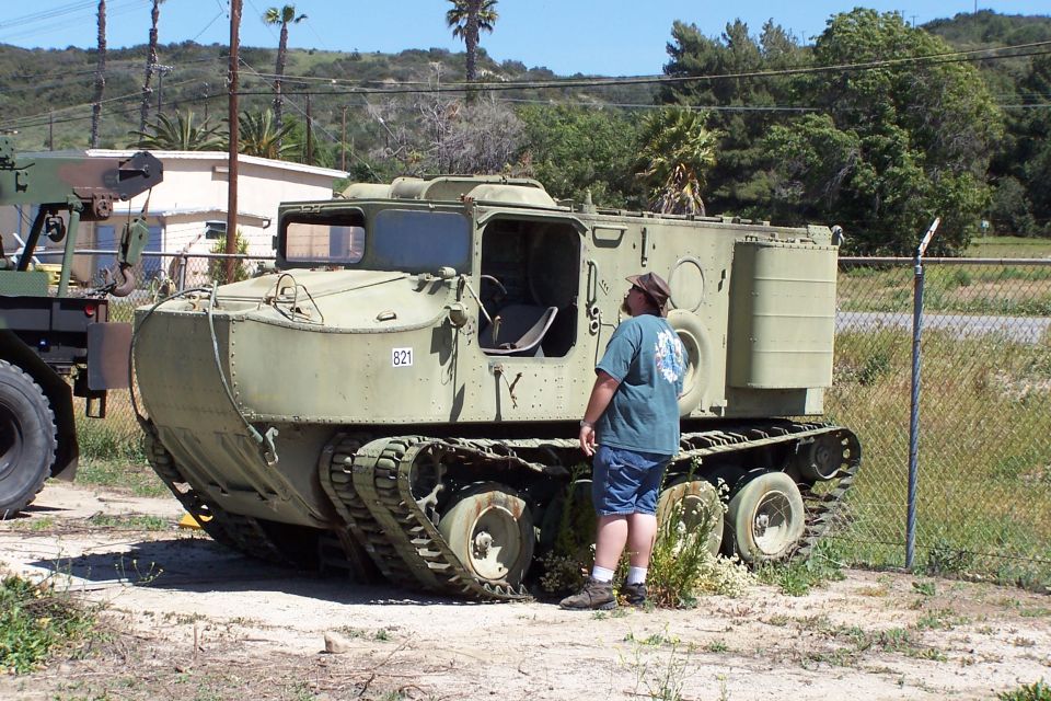 Olive drab tracked vehicle with a man standing next to it