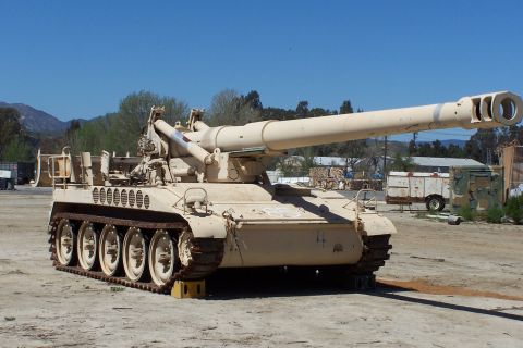 1990 Ford Bronco - A self-propelled howitzer sits in an outdoor lot under a clear blue sky.