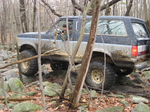 1991 Ford Bronco - This Ford Bronco is shown off-roading through a rocky, wooded area.