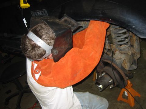 1995 Ford Bronco - A person in welding gear works on the rear suspension of a 1995 Ford Bronco.