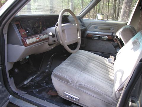 1991 Ford LTD Crown Victoria - The interior of a 1991 Ford Crown Victoria LTD, a velour bench seat and wood-grain trim on the dashboard.
