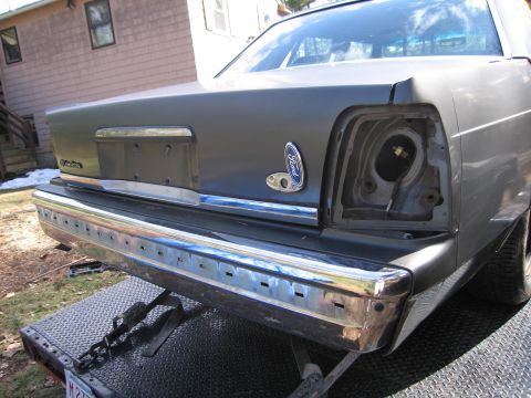 1991 Ford LTD Crown Victoria - Rear view of a gray sedan, likely a 1991 Ford Crown Victoria LTD, showing a missing taillight and chrome bumper detail.
