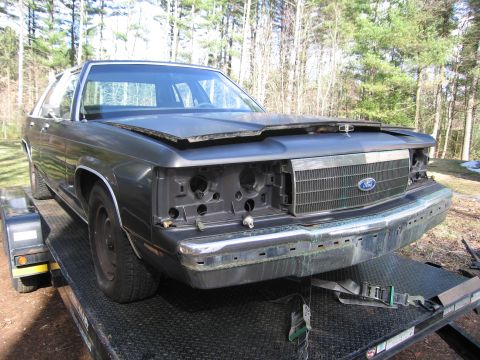 1991 Ford LTD Crown Victoria - This Ford Crown Victoria is missing its headlights and grille, and is being transported on a trailer.