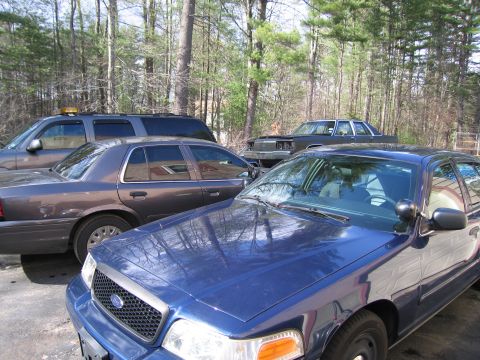 1991 Ford LTD Crown Victoria - Multiple vehicles parked outdoors, including a blue police car and a gray sedan.