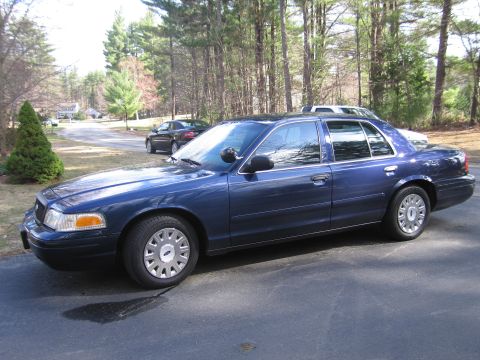 1991 Ford LTD Crown Victoria - A blue sedan is parked on an asphalt surface with trees in the background.