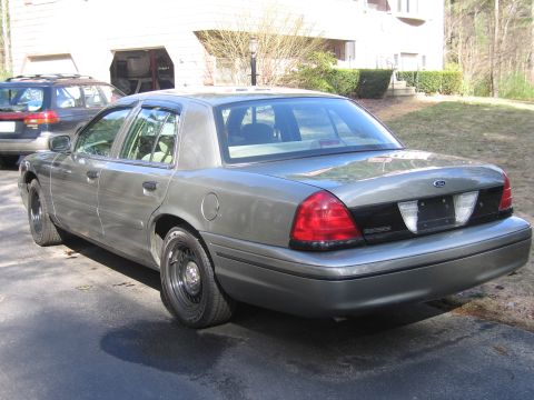 1991 Ford LTD Crown Victoria - A gray 1991 Ford Crown Victoria LTD sedan is parked in a driveway, seen from the rear three-quarter angle. A second vehicle is visible behi…