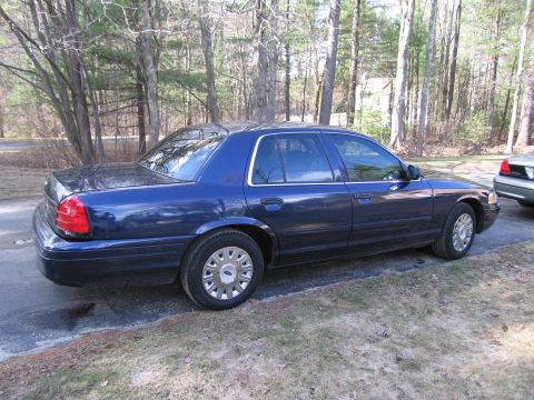 1991 Ford LTD Crown Victoria - A blue sedan is parked on a driveway next to another vehicle, with trees in the background.