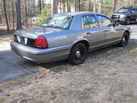 1991 Ford LTD Crown Victoria - A gray sedan is parked on the side of the road, with another SUV visible in the background.