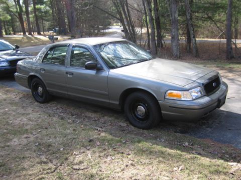 1991 Ford LTD Crown Victoria - A gray Ford Crown Victoria sedan is parked on the side of a road with trees in the background.