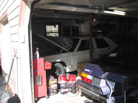 1991 Ford LTD Crown Victoria - A white 1991 Ford Crown Victoria LTD is parked in a garage with its hood up, beside a blue Saab hatchback.