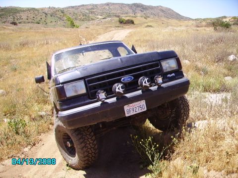 1990 Ford Bronco - Black 1990 Ford Bronco navigating an off-road trail with a California license plate.