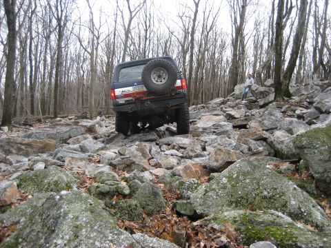 1991 Ford Bronco - This 1991 Ford Bronco is tackling a challenging rocky terrain in a wooded area.