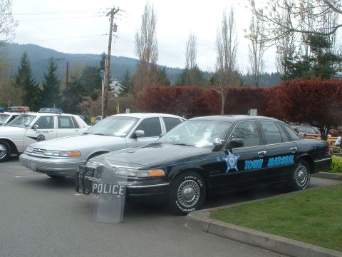 1987 Ford Crown Victoria LTD - Two police vehicles are parked side-by-side, one marked 'Town Marshal' and the other with a 'POLICE' shield.