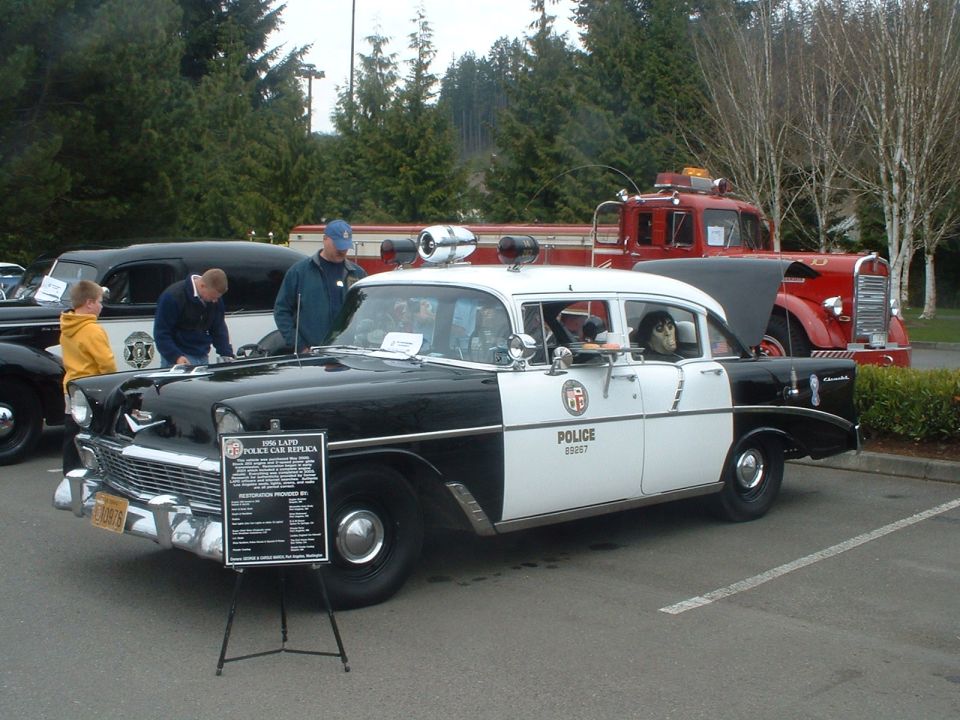 Black and white 1956 police car replica with "POLICE" text on the door