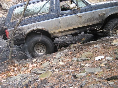 1991 Ford Bronco - A Ford Bronco navigates a challenging, off-road environment with visible mud and debris.