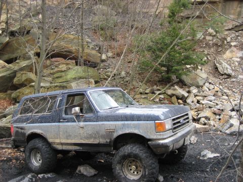 1991 Ford Bronco - This 1991 Ford Bronco navigates a challenging rocky trail, covered in mud from its off-road adventure.
