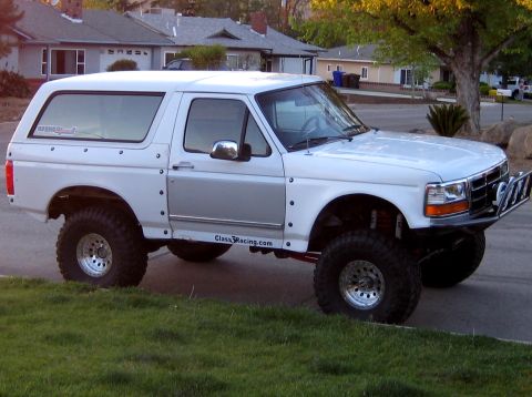 1996 Ford Bronco - Passenger-side three-quarter front view of a white 1992-96-body Ford Bronco built prerunner-style, with a suspension lift, riveted fibergla…