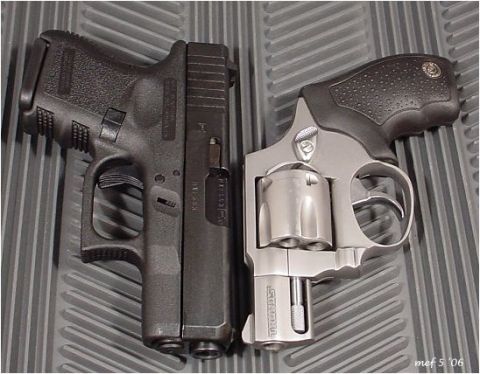 1998 Ford Crown Victoria - A black Glock pistol is shown next to a silver Taurus revolver on a textured gray surface. The image is dated 'mef 5 '06'.