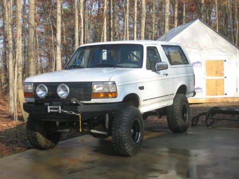 1996 Ford Bronco - White full-size Ford Bronco lifted on black wheels with mud-terrain tires, fitted with a front winch bumper and dual round driving lights,…