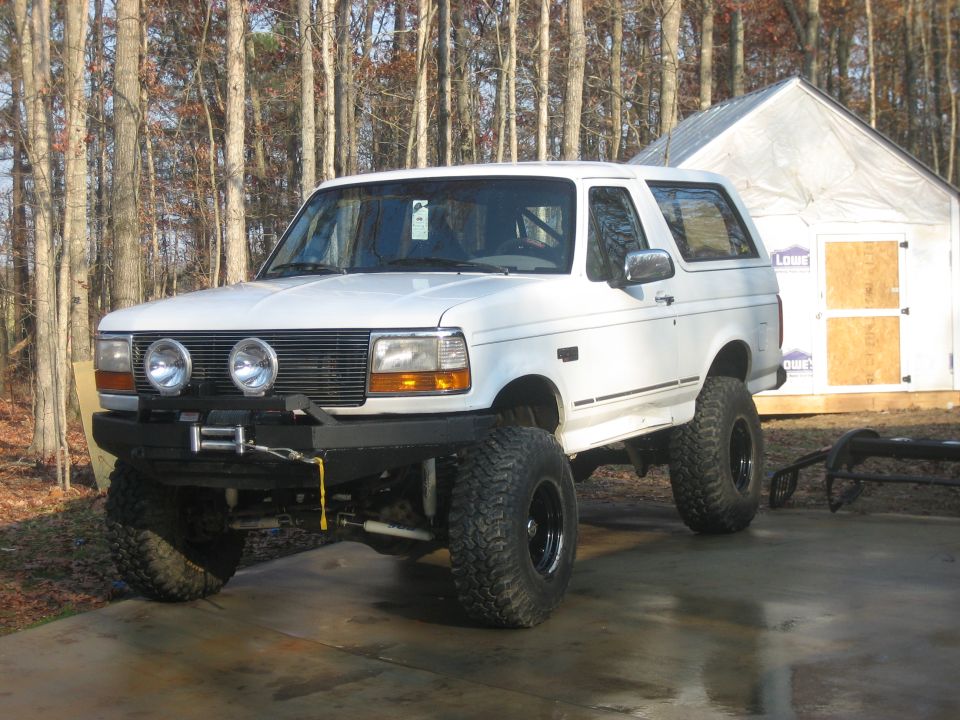 White lifted full-size Ford Bronco with winch bumper, front three-quarter view