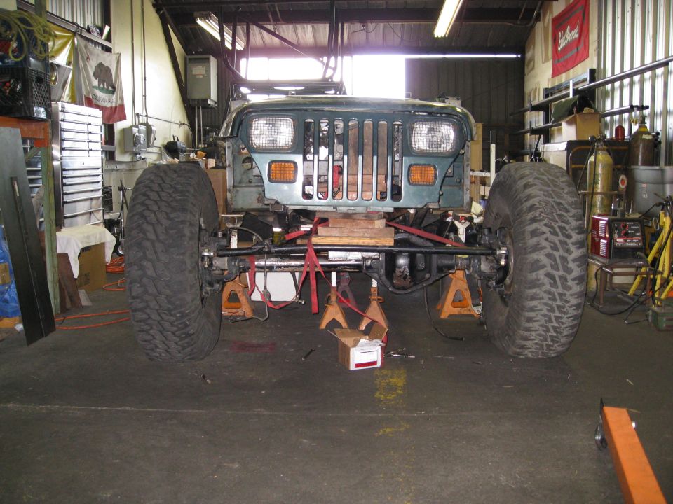Jeep Wrangler on jack stands in a garage, front end visible, large tires