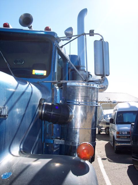 1981 Kenworth W900A - Close-up of a truck's exhaust stack and air intake system, with other vehicles visible in the background.