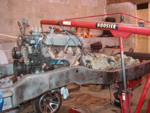 1991 Ford Bronco - Engine and transmission assembly being worked on, suspended above a vehicle frame in a workshop.