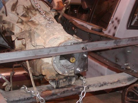1991 Ford Bronco - Close-up view of a vehicle's transmission and transfer case assembly, suspended by chains during disassembly.