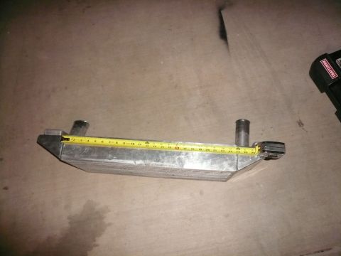 1996 Ford Probe - A silver intercooler is measured with a yellow tape measure on a concrete floor.