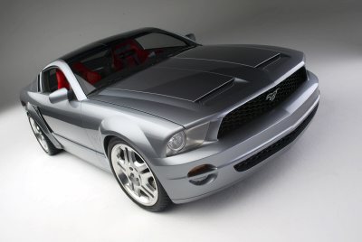 2005 Ford Mustang - A silver 2005 Ford Mustang is shown from a 3/4 front angle, highlighting its aggressive styling and red interior.