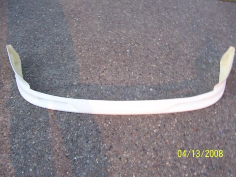 1994 Ford Probe - A white car bumper part is shown on a paved surface, with mounting tabs visible on the sides.