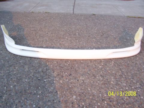 1994 Ford Probe - A white front bumper part is shown resting on an asphalt surface. The image includes a date stamp of 04/13/2008 and a SuperMotors.net water…