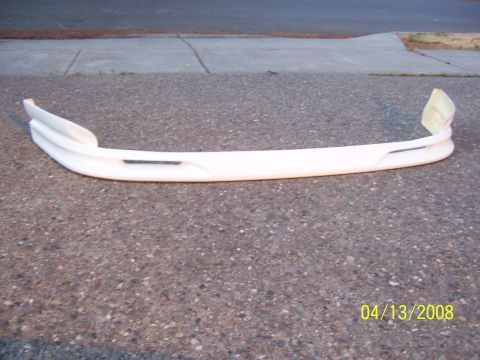 1994 Ford Probe - A white aftermarket front bumper lip is shown resting on a paved surface.