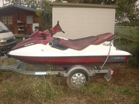 1994 Ford Bronco - A Bombardier jet ski is parked on a trailer in front of a building.