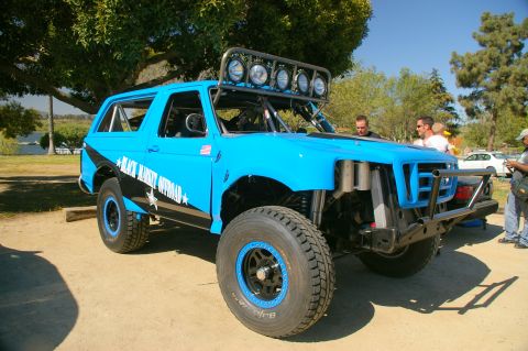 1986 Ford Bronco - Modified blue Ford Bronco with off-road upgrades and custom graphics is parked outdoors.