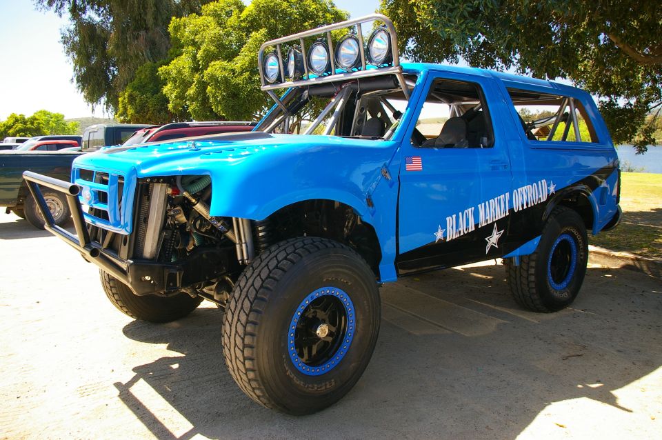 Blue Ford prerunner SUV with tube bumper, long-travel suspension, roof light bar and beadlocks