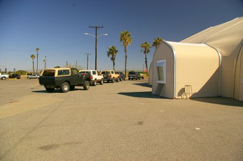 1986 Ford Bronco - Several SUVs are parked in a lot next to a large tent structure.