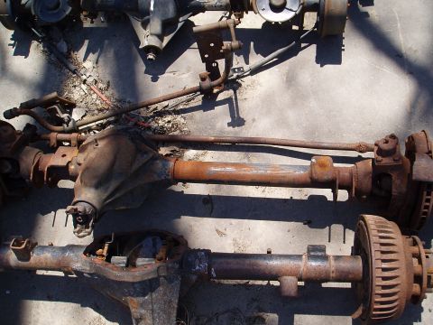 1978 Ford Bronco - These are two old, rusty vehicle axles. One appears to be a front axle with steering components.