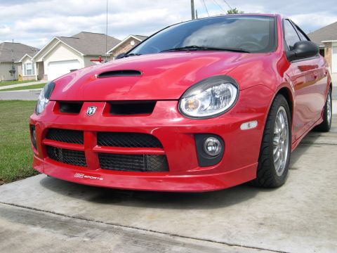 1997 Ford Probe - A red Dodge Neon SRT-4 is parked on a concrete driveway in front of a suburban house.