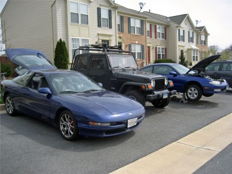 1993 Ford Probe - Three vehicles are parked in a driveway, including a blue 1993 Ford Probe with its hatch open.