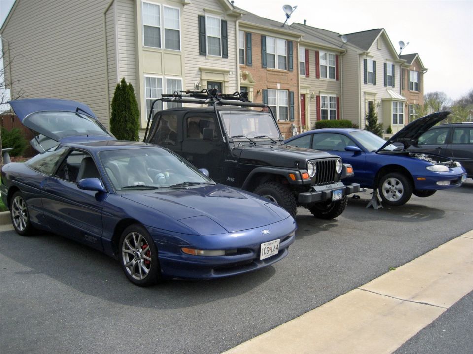 Blue 1993 Ford Probe with rear hatch open, parked in front of townhouses