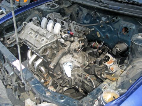 1993 Ford Probe - The engine bay of a blue car is shown with the engine mostly removed, revealing the transmission and other components.