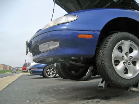 1993 Ford Probe - Front view of a blue 1993 Ford Probe on jack stands with its hood open, parked next to another vehicle.
