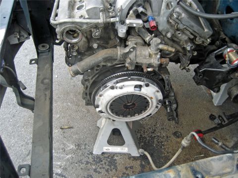 1993 Ford Probe - Engine and transmission assembly, likely removed from a vehicle, is supported by jack stands.