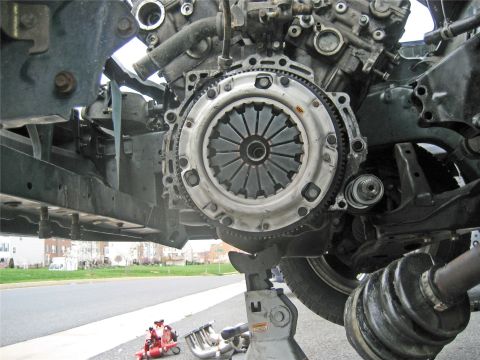 1993 Ford Probe - Close-up view of a vehicle's engine and clutch assembly, supported by jack stands, with exhaust components nearby.