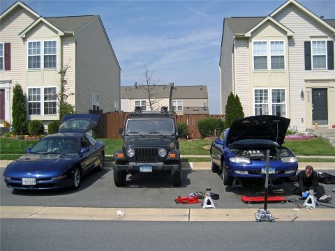 1993 Ford Probe - Three cars are parked in a residential driveway, with one undergoing maintenance.
